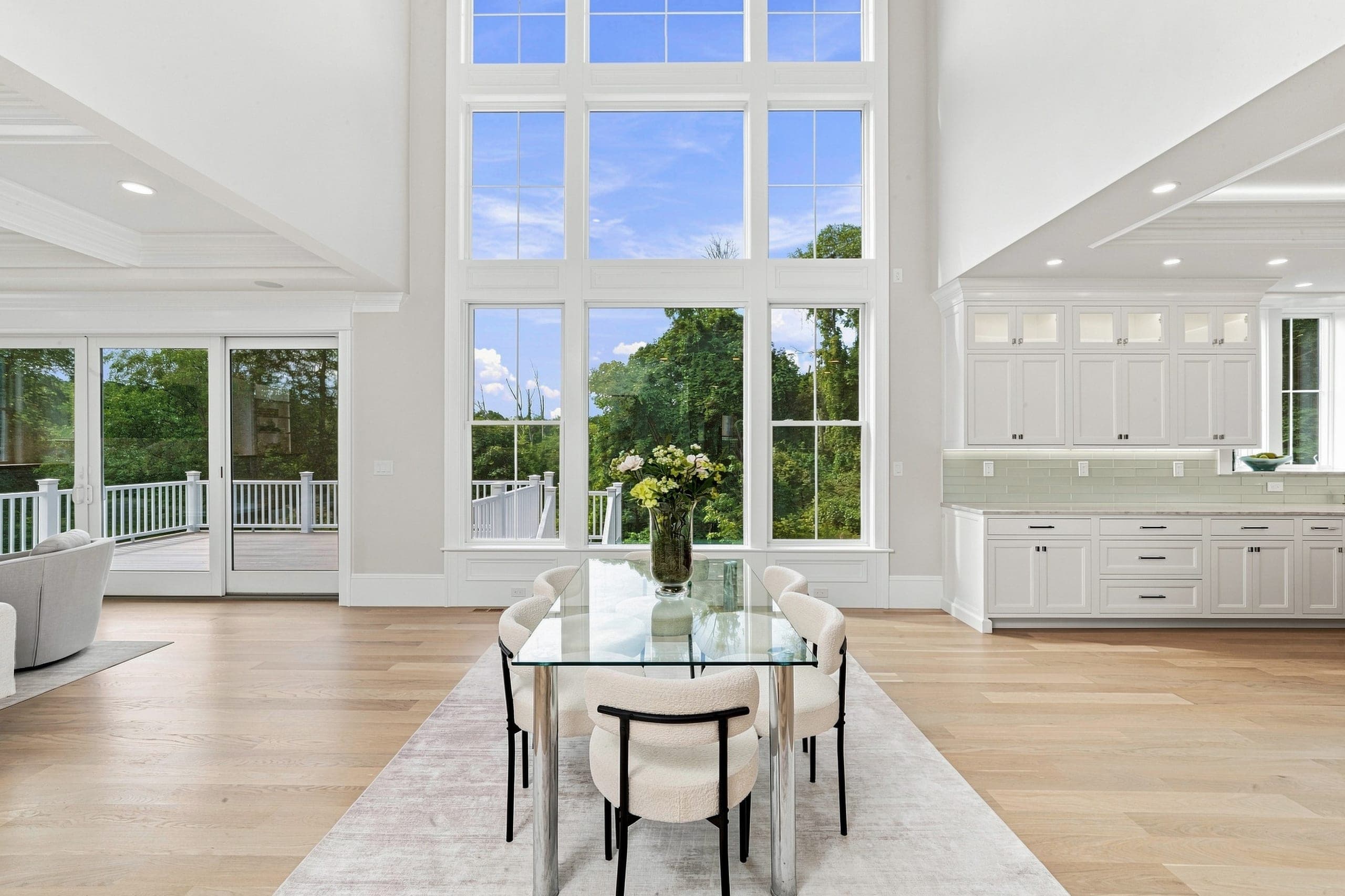 Sunlit foyer and staircase with a tall window looking out onto mature summer landscaping