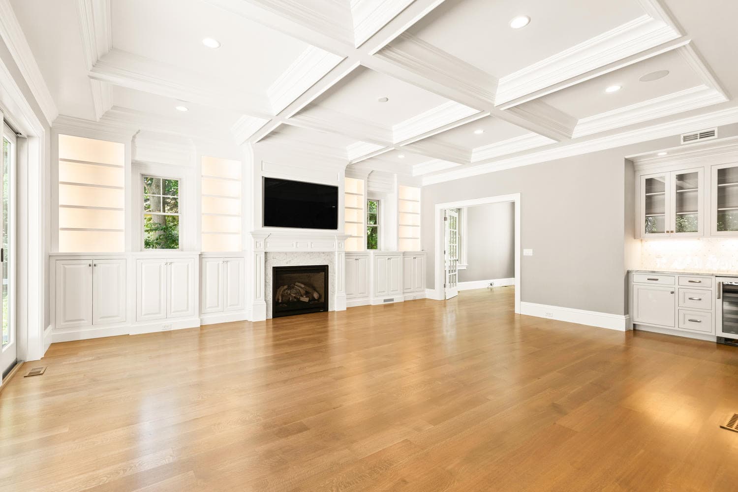 Home office with floor-to-ceiling French doors on three sides, oak floors, and built-in shelving