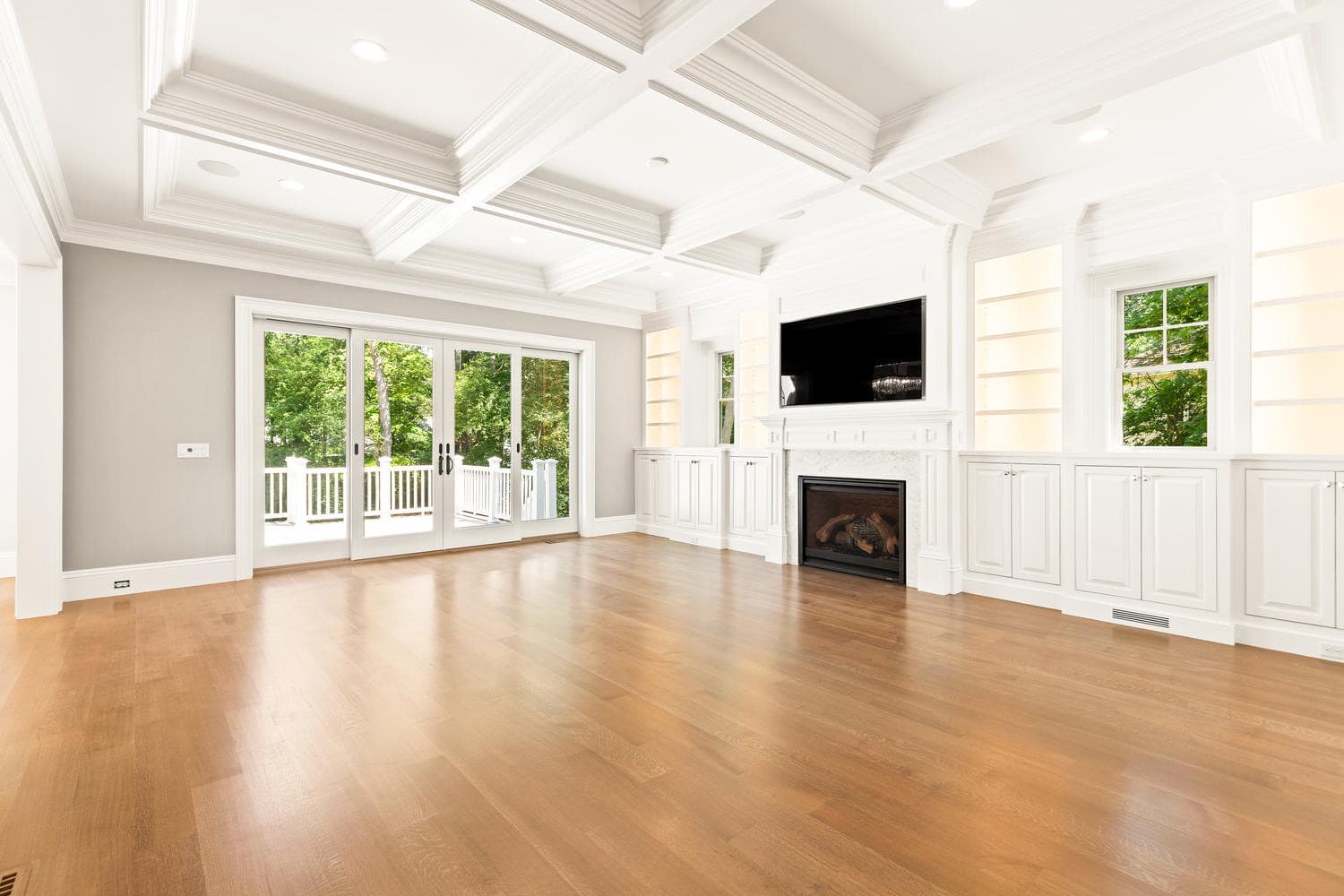 Family room with dramatic coffered ceiling, gas fireplace, full-wall built-ins, and French doors to deck