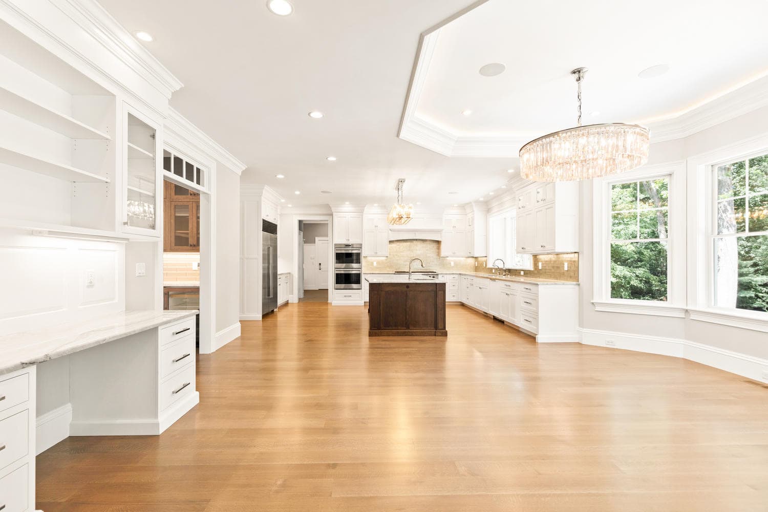 Kitchen and dining area with tray ceiling, crystal drum chandelier, butler's pantry, and bay windows