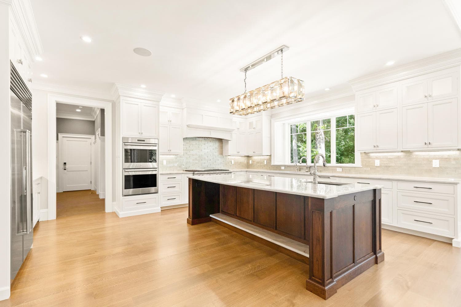 Kitchen from secondary angle showing white cabinetry, walnut island, subway tile backsplash, and Sub-Zero appliances