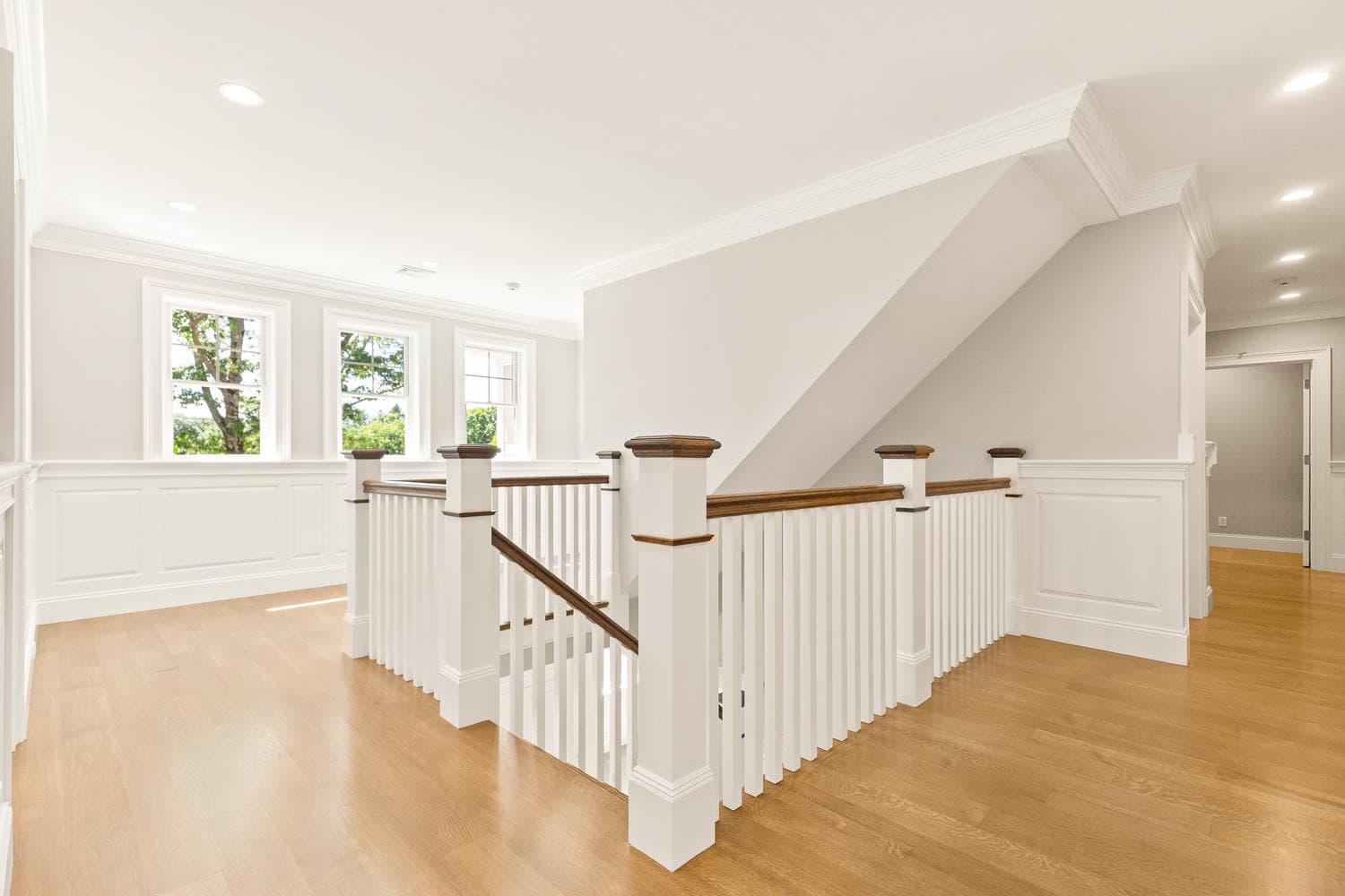 Second floor landing with wainscoting, oak railings, and white balusters