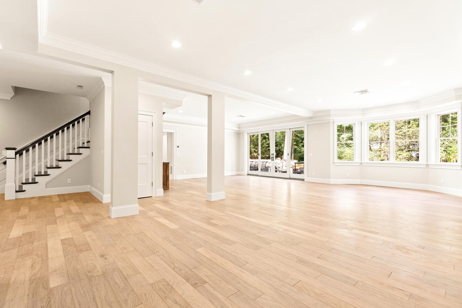 Open plan living with light oak floors, crystal chandeliers, and exterior views