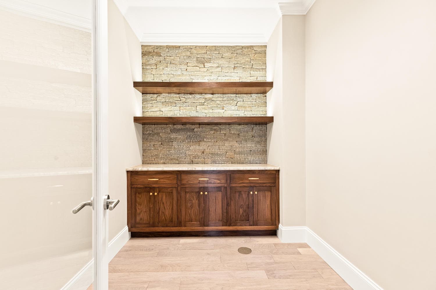 Bar and wine room with stacked stone accent wall, floating walnut shelves, and marble countertop