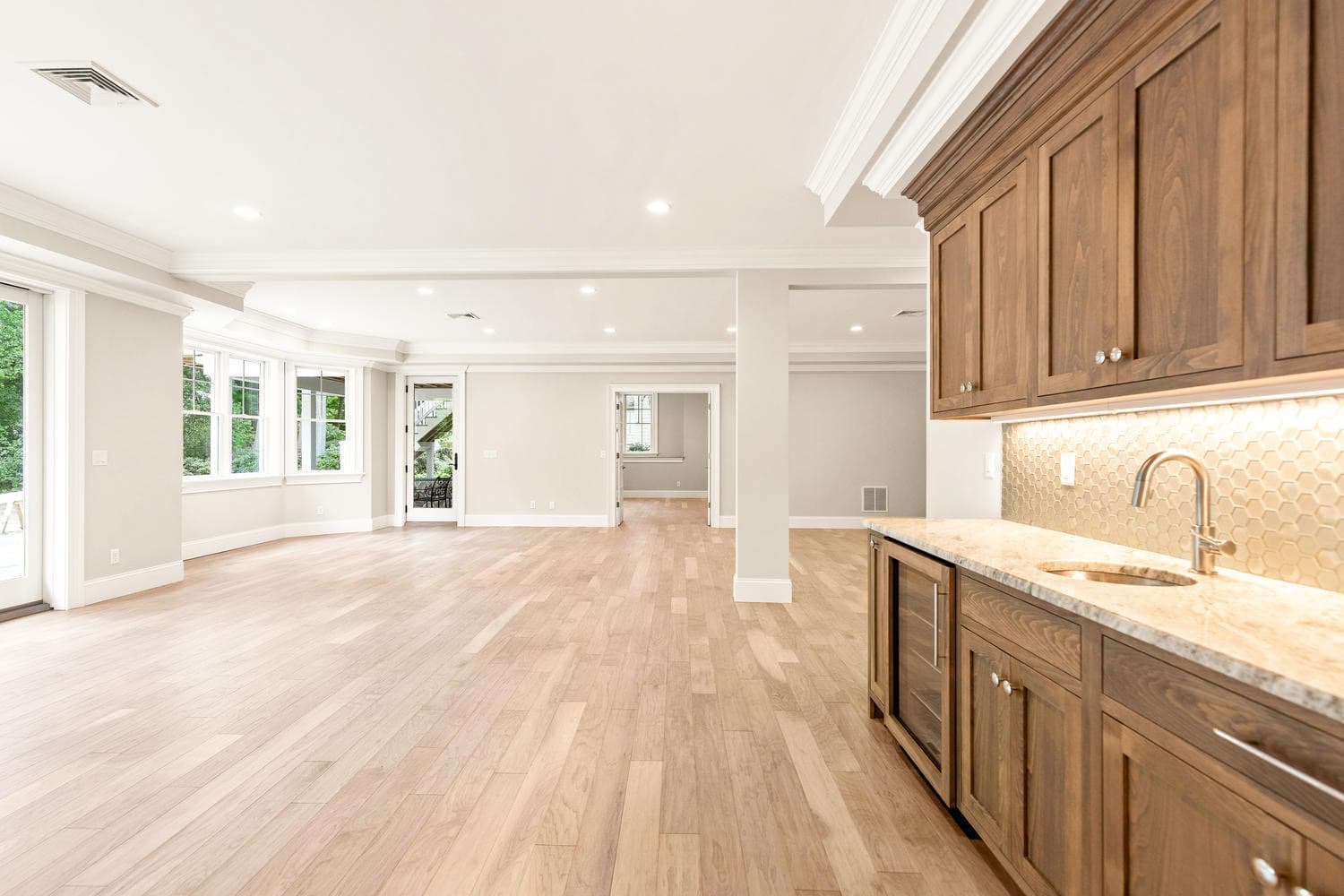 Lower level wet bar with walnut cabinetry, hexagonal tile backsplash, and beverage refrigerator