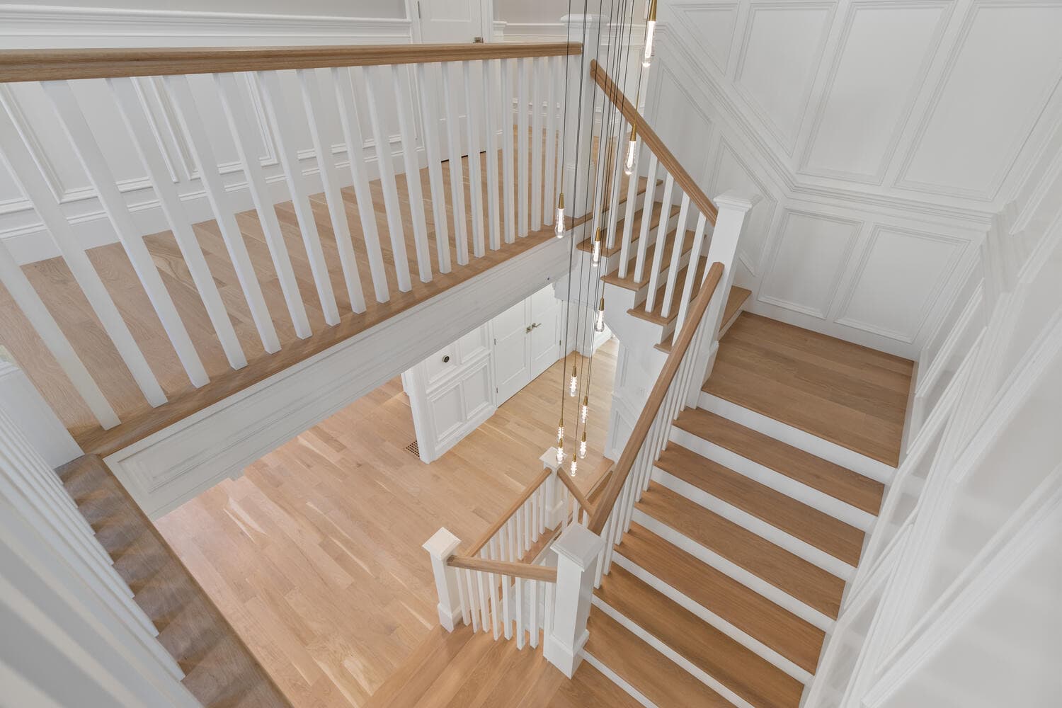 View from above showing three-floor stairwell with white spindles and oak treads