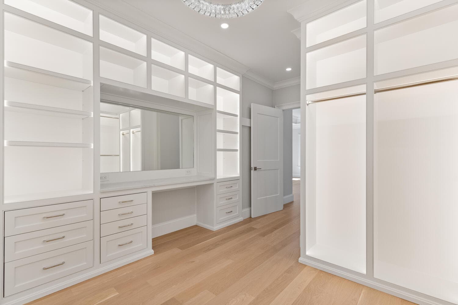 Second walk-in closet with white built-ins and crystal chandelier