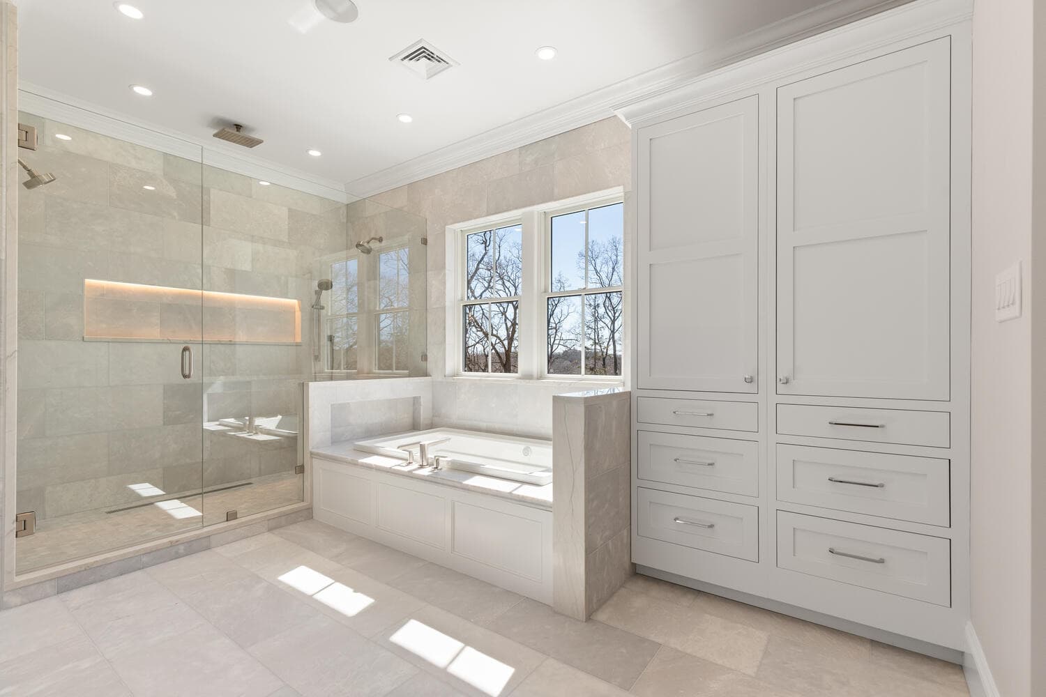 Primary bathroom showing full glass shower enclosure and floor-to-ceiling tile