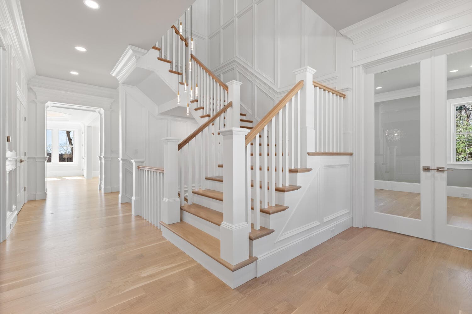 Dramatic staircase with cascading pendant lights and floor-to-ceiling wainscoting