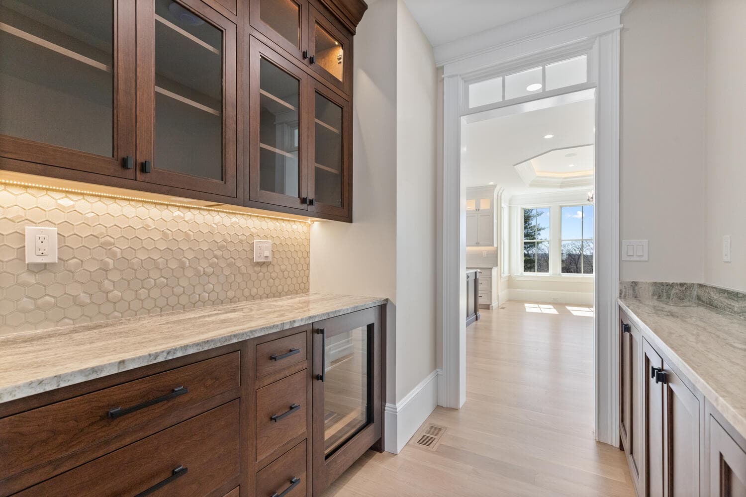 Butler's pantry with dark walnut cabinetry, hexagonal backsplash, and wine refrigerator