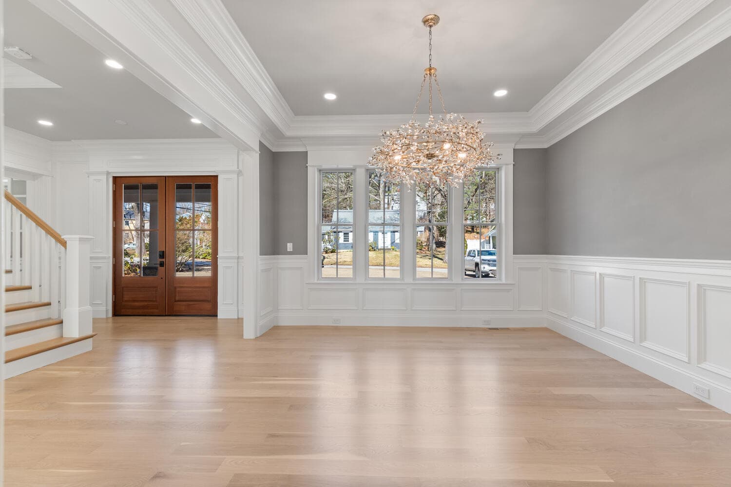 Dining room with crystal branch chandelier, wainscoting, and view to foyer