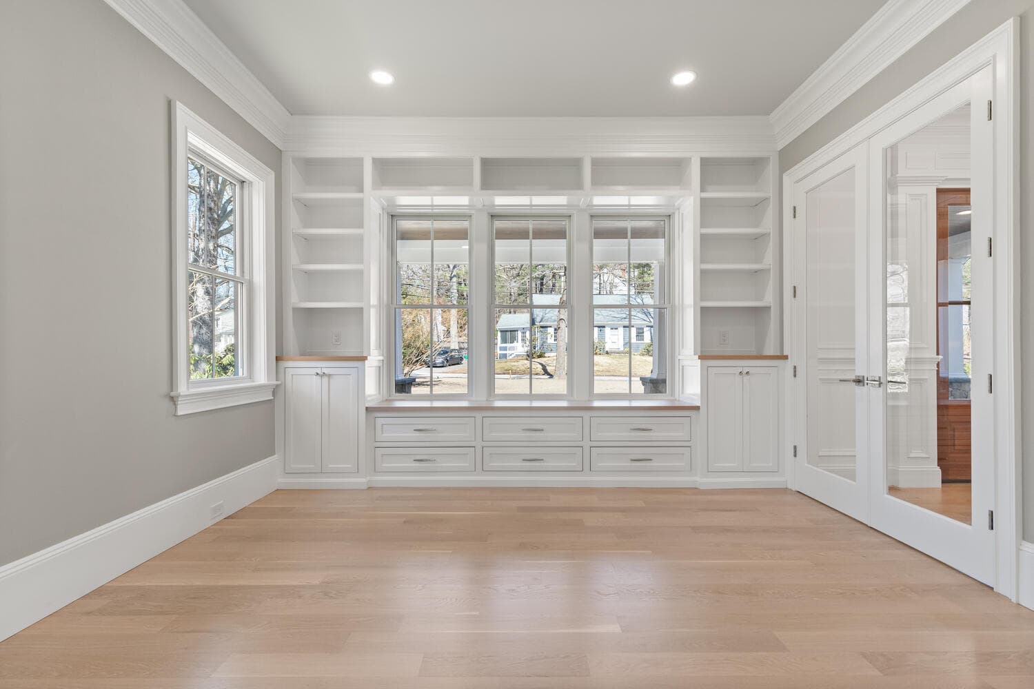 Office with floor-to-ceiling built-in bookshelves, window seat, and French doors