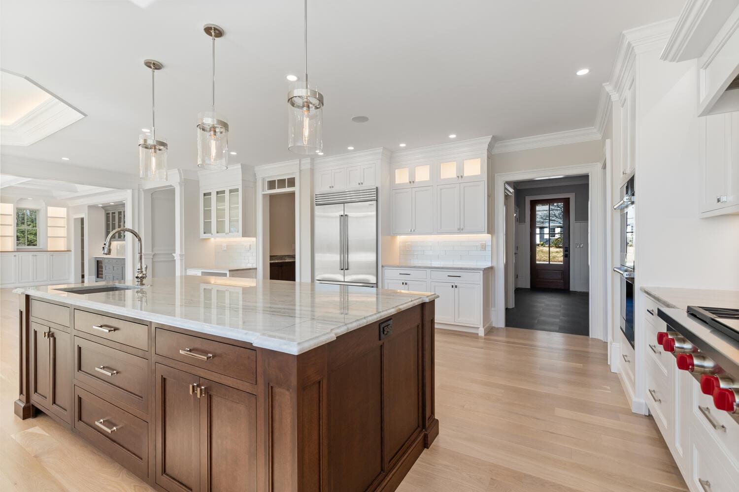 Kitchen island detail with dark cherry cabinetry, Wolf range, and glass pendants
