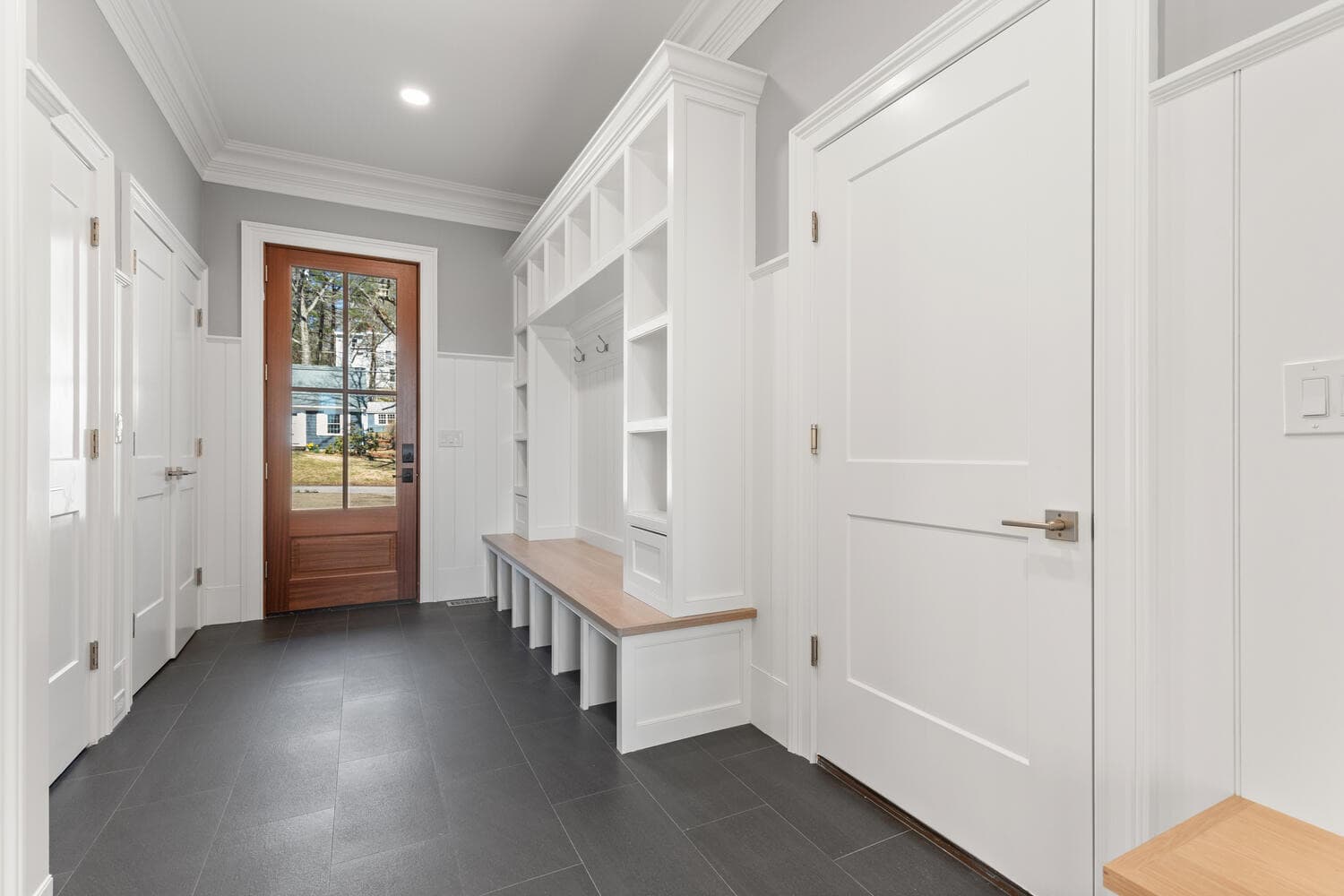 Mudroom with slate tile floors, built-in bench with cubbies, and mahogany door