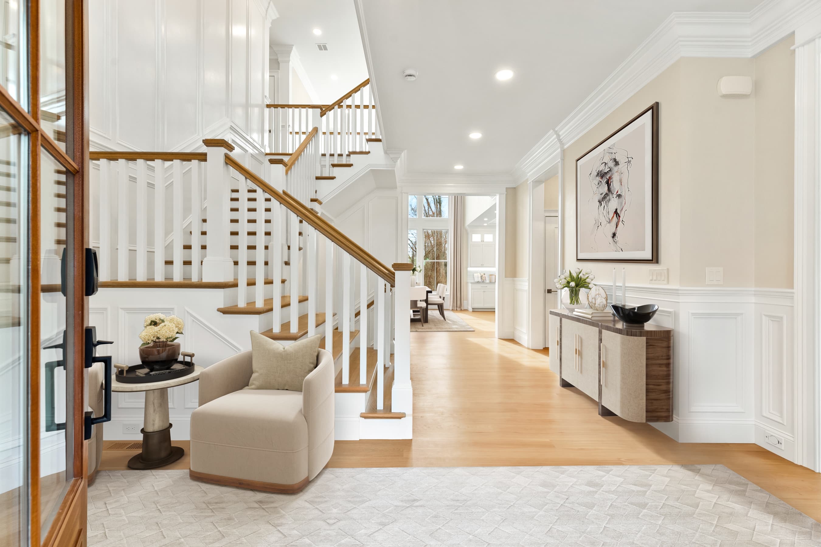 Grand foyer with two-story staircase, wainscoting, modern art, and designer furnishings — virtually staged