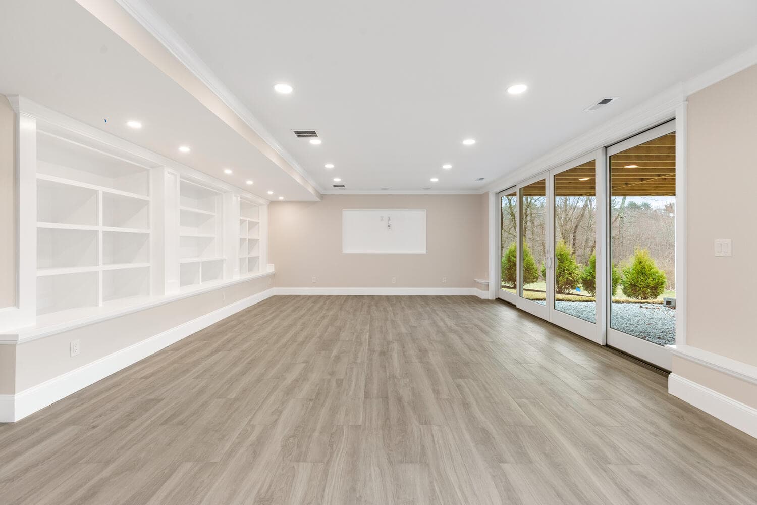 Lower level recreation room with 16-foot sliding glass doors and white built-ins