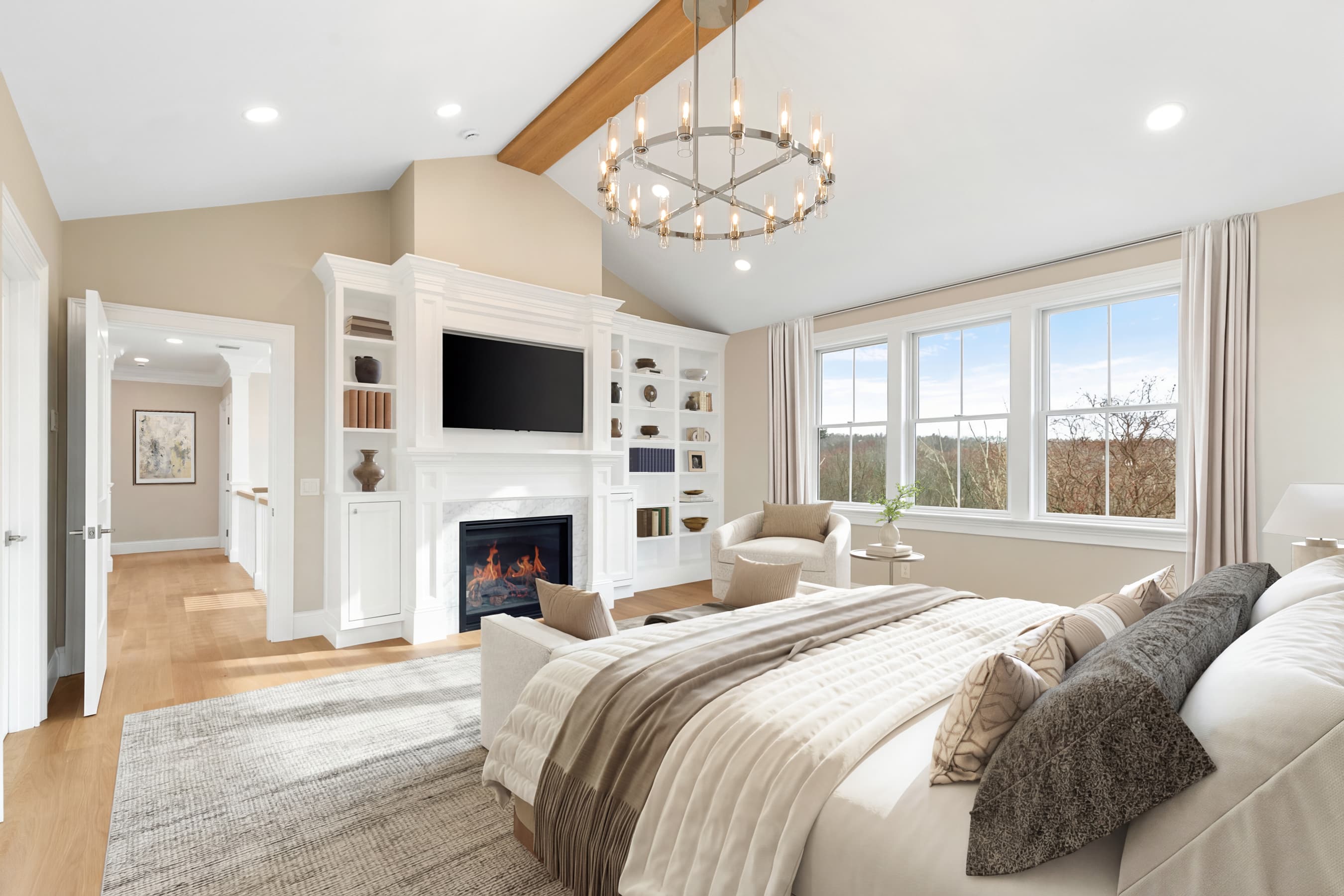 Primary suite with fireplace built-ins, vaulted ceiling, and chandelier — virtually staged