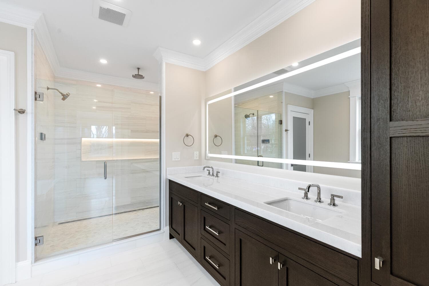 Primary bathroom with marble dual vanity, lighted mirrors, and dolomite shower