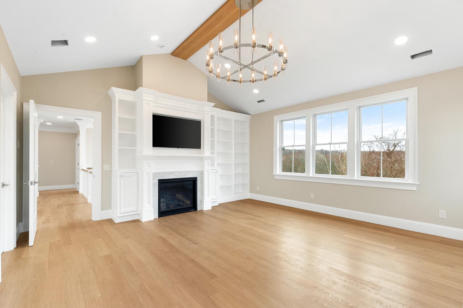 Primary bedroom with vaulted ceiling, exposed beam, fireplace, and crystal chandelier